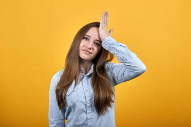 Gömlekli hasta esmer kadın elini alnına koyuyor, başı ağrıyor.