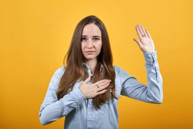 Çekici bir kadın söz veriyor, elini göğsüne koyuyor ve kameraya avuç içi çekiyor.