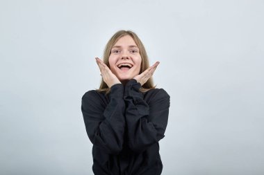 Tişörtlü neşeli bayan avuçlarını çenesinde tutuyor, gülümsüyor, kameraya bakıyor.