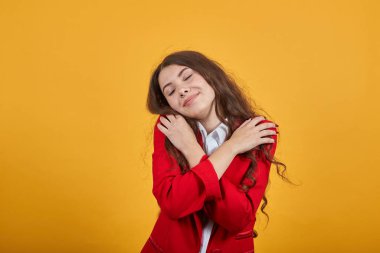 Çekici, neşeli, genç bir kadın ellerini çapraz tutuyor, kendine sarılıyor, güzel.