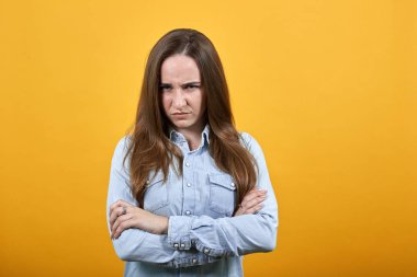 Kot mavi gömlekli, ciddi bir beyaz kadın ellerini çapraz yapmış, agresif görünüyor.