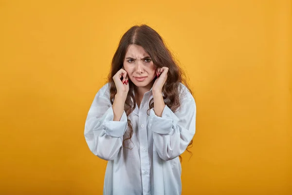 Ongelukkige vrouw in wit shirt gesloten oren met handen, op zoek teleurgesteld — Stockfoto