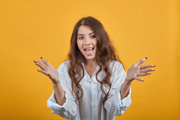 Verrast vrouw in wit shirt spreidt handen, tonen tong, glimlachen — Stockfoto