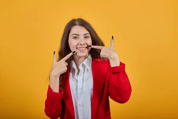 Mujer alegre en camisa blanca y chaqueta roja sonriendo, señalándole con los dedos —  Fotos de Stock