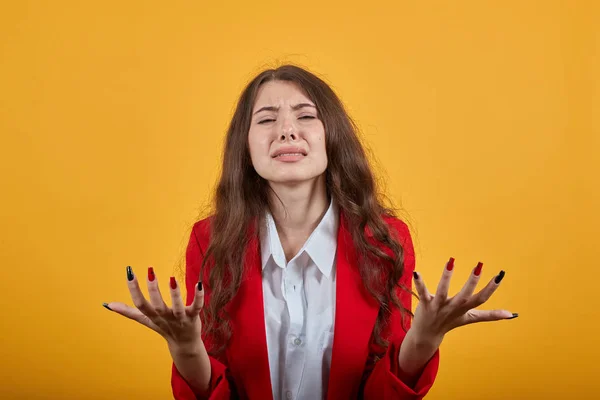 Teleurgestelde vrouw in wit shirt en jas spreidt handen, ziet er ongelukkig uit — Stockfoto