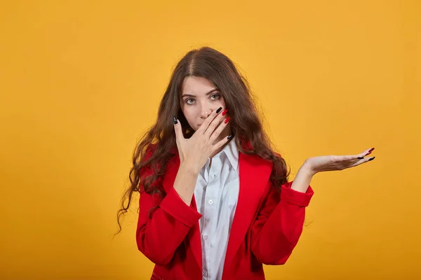 Aantrekkelijke dame in overhemd en jas bedekte mond met de hand, wijzende palm opzij — Stockfoto