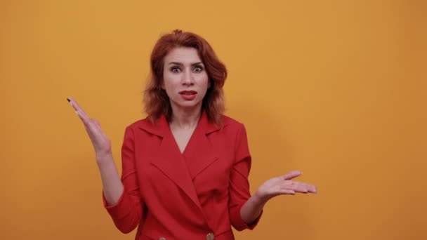 Confused woman wearing fashion red jacket spreads hands, looking disappointed. — Stock Video
