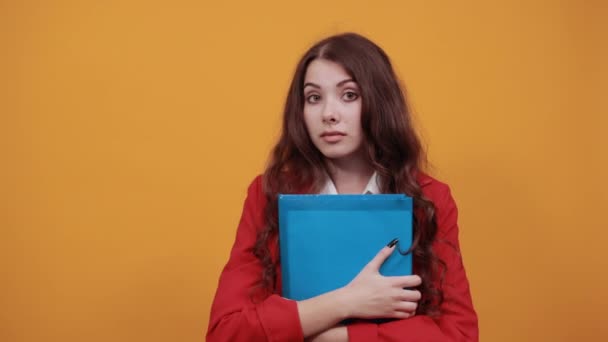 Allvarlig brunett ung kvinna som håller blå mapp, tittar på kameran — Stockvideo
