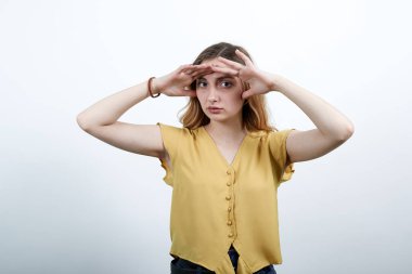 Çekici bir genç kadın. Elini alnına koyup, mesafeye bakıyor.