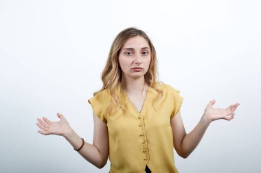 Hayal kırıklığına uğramış kadın kameraya el yayıyor, mutsuz, moda sarısı gömlek giyiyor.