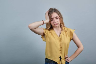 Hasta kadın ellerini başının üstünde tutuyor, baş ağrısı çekiyor, elini kemere koyuyor.