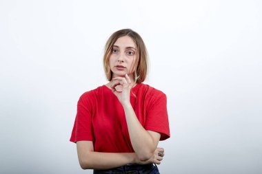 Kadın çenesini kapalı tutuyor, elleri kemerde, konu hakkında düşünüyor.