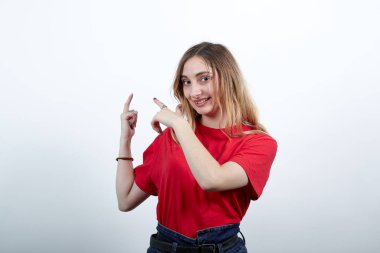 Neşeli kadın kameraya bakıyor, parmaklarını duvara doğrultuyor.