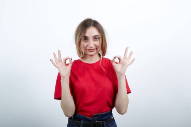 Çekici kadın parmaklarıyla jest yapıyor, kameraya bakıyor.