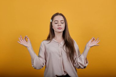 Sakin, genç, beyaz bir kadın parmaklarını bir arada tutuyor. Meditasyon, rahatlama.