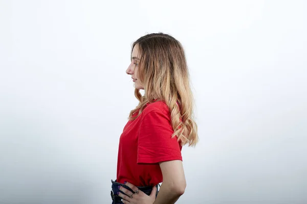 Giovane donna caucasica in camicia rossa rimanendo lateralmente, tenendo la mano sulla cintura — Foto Stock