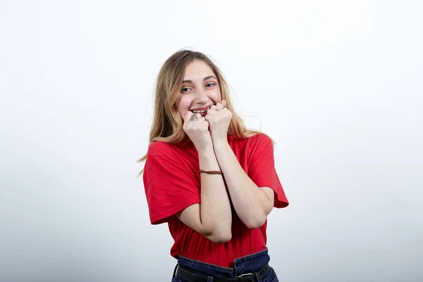 Ευτυχισμένη γυναίκα με κόκκινο πουκάμισο χαμογελώντας, δαγκώνοντας καρφιά, καλυμμένο στόμα με γροθιές — Φωτογραφία Αρχείου