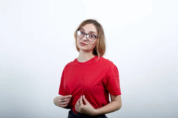 Atractiva mujer caucásica tira de la camisa con los dedos, serio —  Fotos de Stock