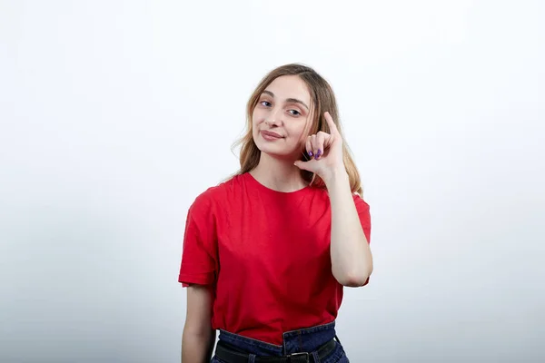 Giovane donna allegra nella moda camicia rossa mantenendo gesto chiamata vicino all'orecchio, sorridente — Foto Stock