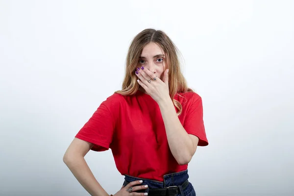 Sorpresa giovane donna bocca coperta con mano, tenendo la mano sulla cintura — Foto Stock