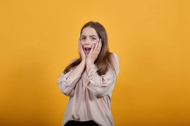 Şaşırmış genç beyaz kadın ellerini yanaklarından ayırmıyor, ağzını açtı.