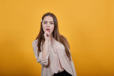 Çekici beyaz kadın, elini dudaklarından ayırmıyor, mutsuz, kafası karışık.