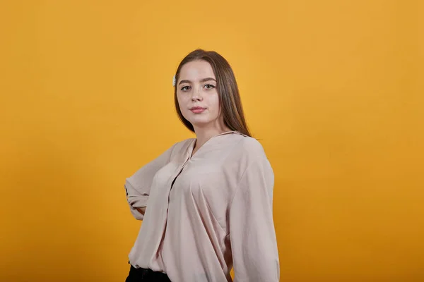 Encantadora mujer en camisa pastel de moda manteniendo la mano en el cinturón, mirando a la cámara — Foto de Stock