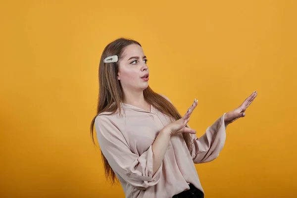 Disappointed caucasian woman in pastel shirt staying sideways, spreads hands — Stock Photo, Image