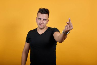 Aggressive caucasian young man showing middle finger at camera.