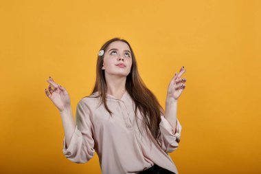 Charming woman looking at camera, keeping fingers crossed, make wish, looking up