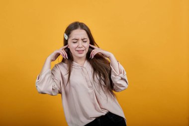 Young disappointed woman closed ears with fingers, squeezing face