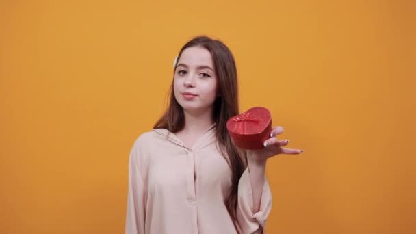 Attractive caucasian young woman keeping red box, doing okay gesture, winks — Stockvideo