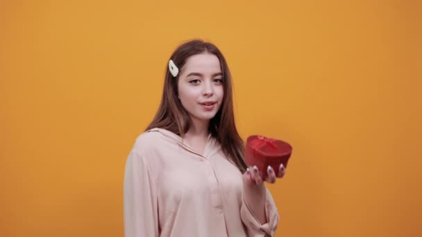 Atractiva mujer caucásica que mantiene la caja roja, sonriendo vistiendo camisa pastel — Vídeo de stock