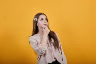 Serious young woman keeping finger on chin, thinking about issue.
