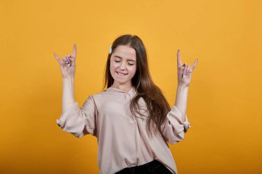 Attractive caucasian woman dancing, enjoying, doing rock gesture, biting lips