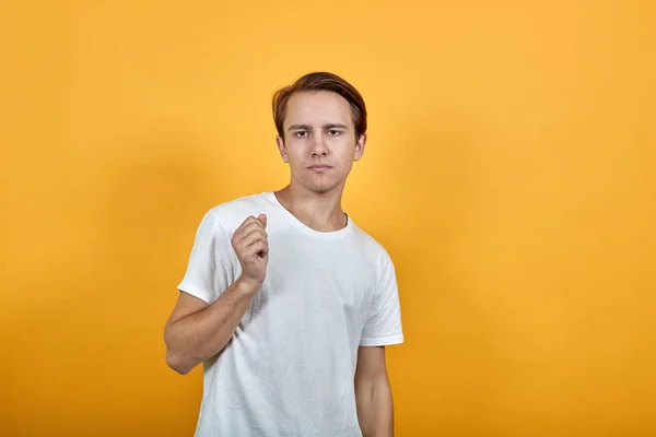 Junger Mann im weißen T-Shirt auf gelbem Hintergrund blickt zuversichtlich nach vorn — Stockfoto
