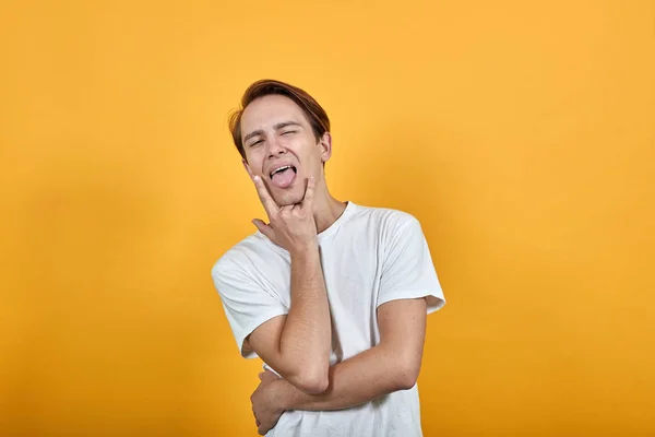 Mann im weißen T-Shirt zeigt Rockstil und streckt amüsant die Zunge heraus — Stockfoto