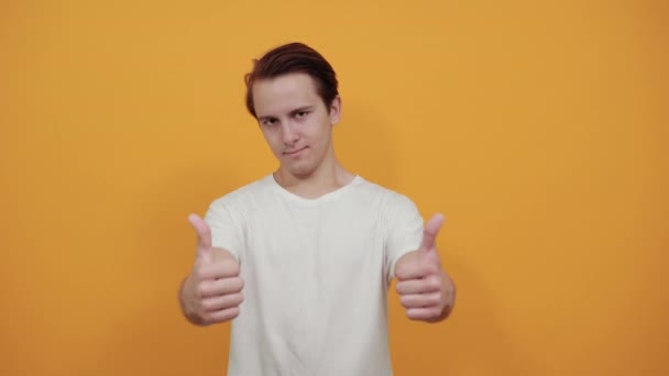 Pulgar hacia arriba gesto positivo joven hombre de negocios en blanco camiseta fondo amarillo — Vídeos de Stock