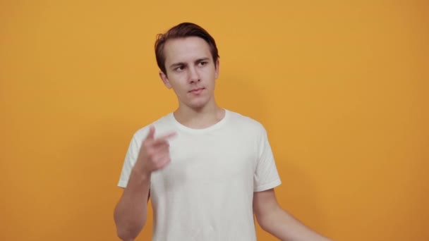 Человек в белой футболке показывает жест, который, как он думает, касается указательного пальца к голове — стоковое видео