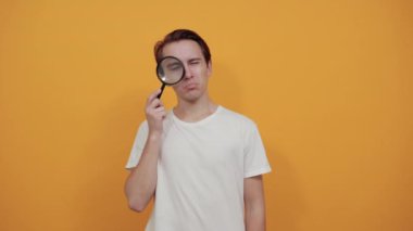 Üzgün adam sivilcenin yanında büyüteç tutuyor.