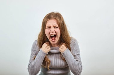 Geniş ağızlı, gri elbiseli arka planda saldırganlık çığlığı atan kadın..