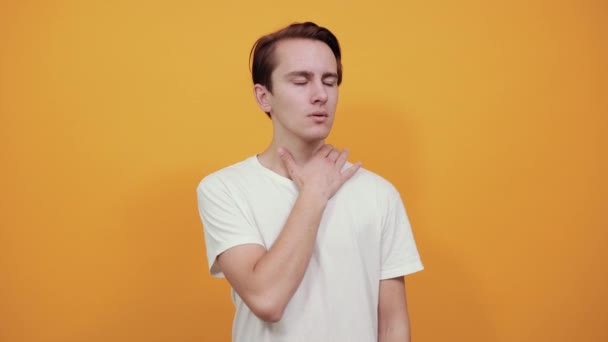 El hombre con camiseta se aferra a su cuerpo a través del dolor de garganta. Resfriado o enfermedad en el hombre — Vídeo de stock