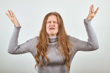 Kızıl saçlı mutsuz genç bir kadın umutsuzluk ve sefalet içinde ellerini kaldırıyor.