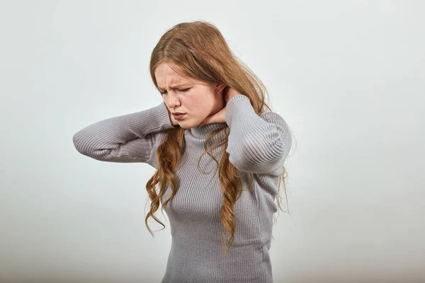 Женщина в свитере с рыжими волосами согнута от боли, держа шею и горло болит — стоковое фото
