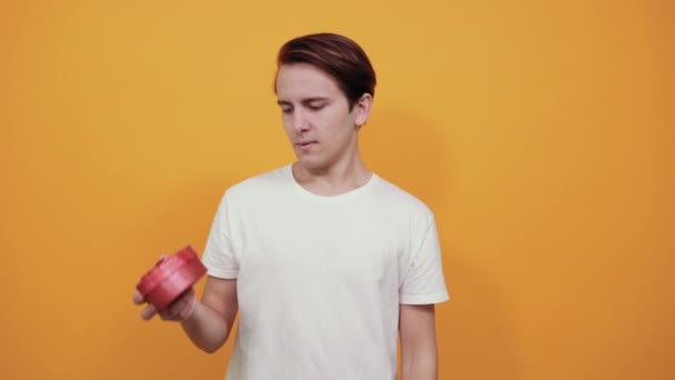 Ein verträumter junger Mann im weißen T-Shirt hält ein Geschenk in Herzform in der Hand — Stockvideo