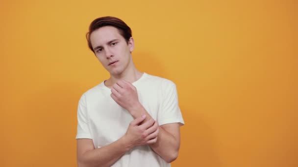 Fiatal jóképű férfi fehér pólóban rimacing kézen fogva gyanús megjelenés — Stock videók