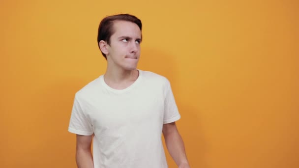 Guy in white t-shirt on yellow background smiles happy and gives thumbs up — Stock Video