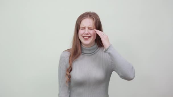 Piękna, rudowłosa kobieta w szarym swetrze kręci palcami wokół głowy — Wideo stockowe