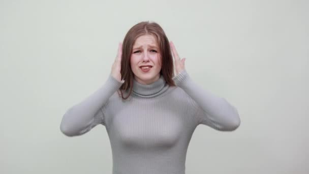 Vrouw in grijs trui houdt haar hoofd met haar handen van verrassing schrik shock — Stockvideo