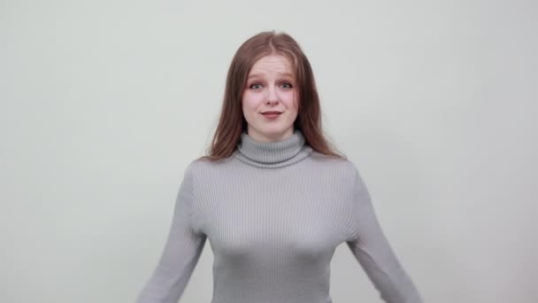 Молодая счастливая рыжая женщина в сером свитере счастлива и подняла руки — стоковое видео